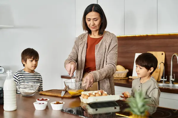 Eine freudige asiatische Großmutter teilt die Freude am Backen von Weihnachtsleckereien mit ihren beiden entzückenden Enkeln. — Stockfoto