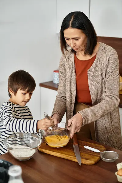 Eine fröhliche Großmutter und ihr Enkel backen gemeinsam festliche Leckereien und umarmen die Feiertagsstimmung. — Stockfoto
