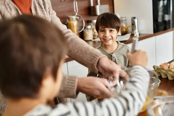 Eine glückliche Großmutter genießt das Backen von Leckereien in der Küche mit ihren verspielten Enkeln. — Stockfoto