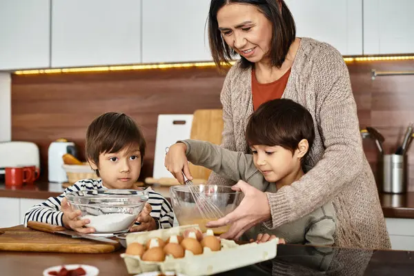 Eine Großmutter bringt ihren Enkeln freudig bei, gemeinsam in einer warmen Küche festliche Leckereien zu backen. — Stockfoto