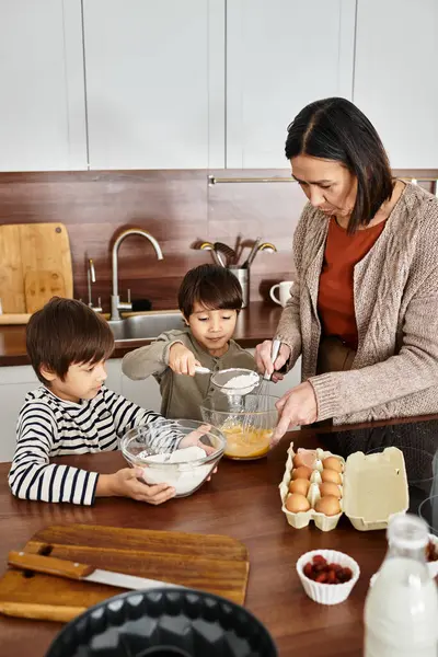Eine fröhliche Großmutter bringt ihren Enkeln in einer gemütlichen Küche das Backen von Leckereien bei. — Stockfoto
