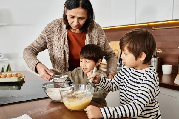 Eine fröhliche Großmutter lehrt ihre Enkel Leckereien backen, während sie sich auf Weihnachten vorbereiten. — Stockfoto