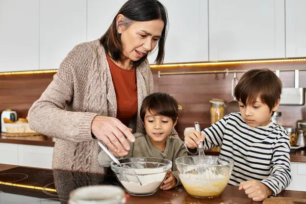 Eine Großmutter bringt ihren Enkeln in ihrer gemütlichen Küche freudig das gemeinsame Backen bei, während Weihnachten naht. — Stockfoto