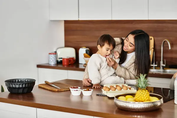 Eine fröhliche Mutter füttert ihren Sohn als Koch in der modernen Küche und feiert die Feiertagsstimmung. — Stockfoto