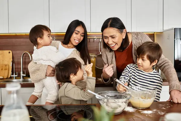 An Asian family joyfully prepares holiday treats, with kids helping adults in a modern kitchen. — Stock Photo