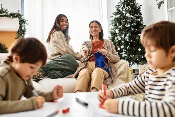 A joyful family connects while knitting and coloring around a beautifully decorated Christmas tree. — Stock Photo