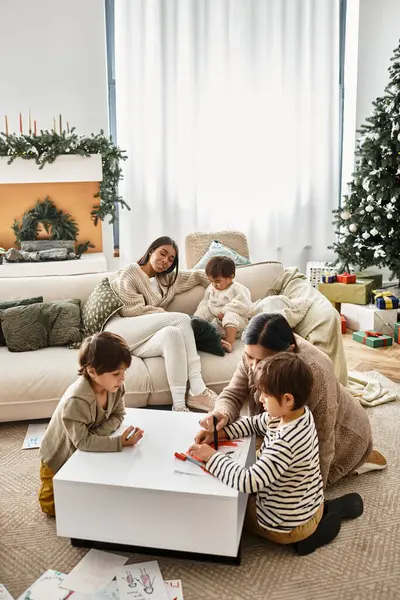 A cheerful Asian family gathers in a modern living room, enjoying festive moments around their Christmas tree. — Stock Photo