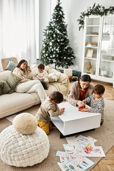 A happy family enjoys quality time together, creating holiday crafts around the Christmas tree in a modern space. — Stock Photo