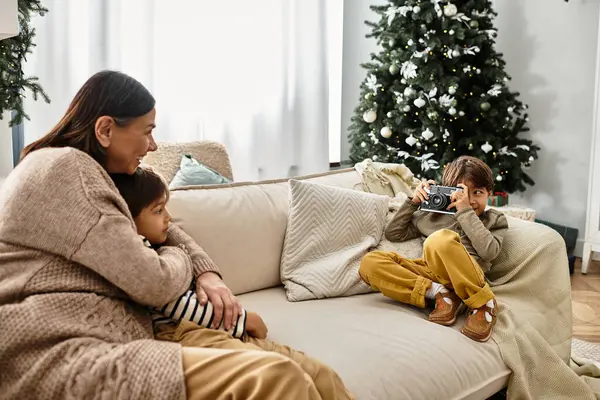 Una familia alegre se reúne alrededor del árbol de Navidad, compartiendo risas y capturando recuerdos en un ambiente cálido. — Stock Photo