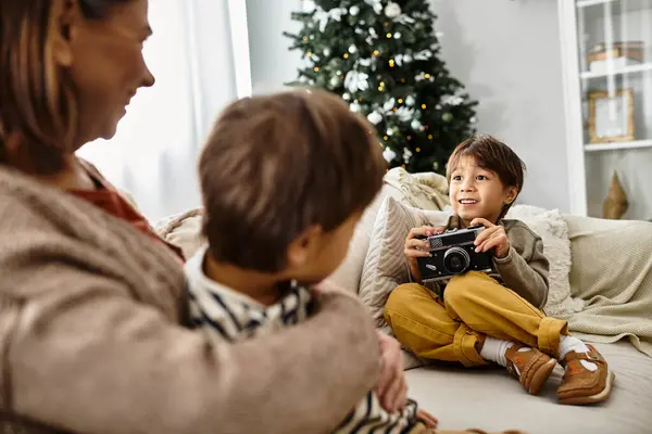 Una familia asiática se reúne alrededor de un árbol de Navidad bellamente decorado, niño tomando fotos en la cámara — Stock Photo