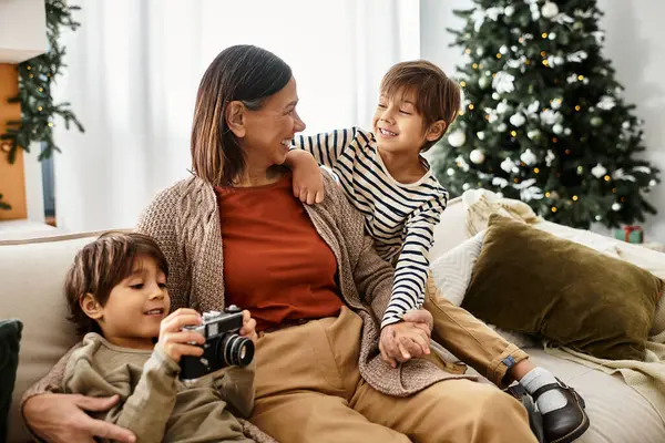 Eine Großmutter lächelt, wenn ihre Enkel spielen und die Weihnachtsstimmung zu Hause genießen. — Stockfoto