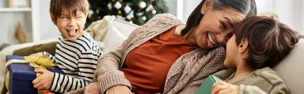 A happy family enjoys each others company while gathering around their beautifully decorated Christmas tree. — Stock Photo