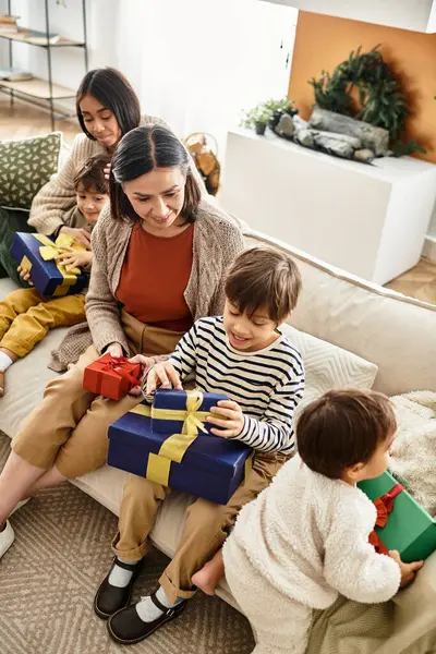 Les membres de la famille se plaisent à ouvrir des cadeaux de Noël ensemble, partageant rire et amour dans leur maison confortable. — Photo de stock