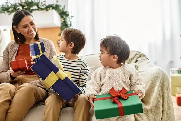 A happy family shares laughter and love, kids opening Christmas presents beside their grandmother. — Stock Photo