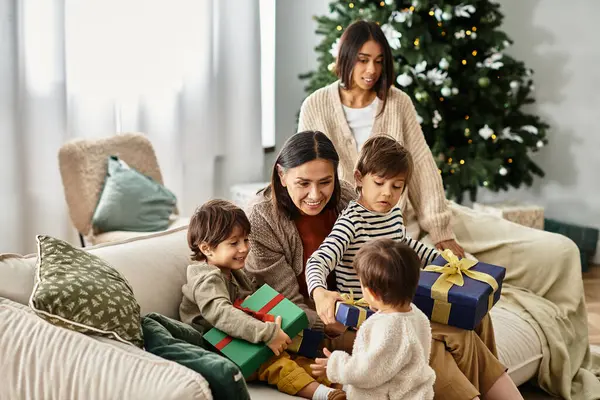 A happy Asian family gathers around the Christmas tree, sharing gifts and laughter during the festive season. — Stock Photo