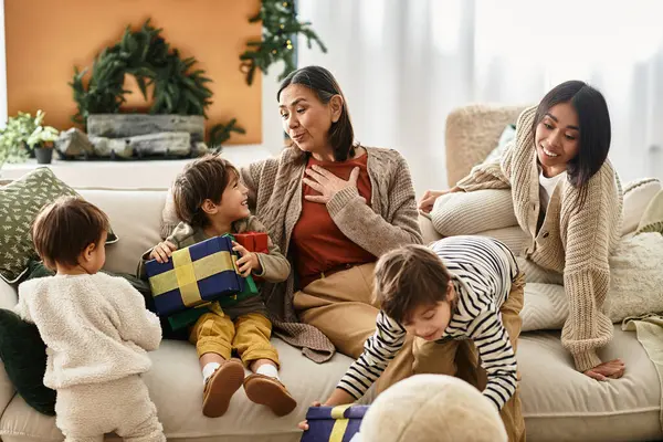 A happy Asian family gathers around a beautifully decorated living room, exchanging Christmas gifts and laughter. — Stock Photo
