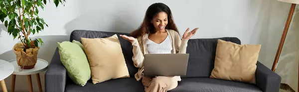 A cheerful woman expresses excitement while chatting on her laptop in a comfortable setting. — Stock Photo