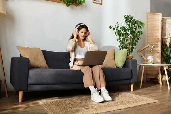 The woman sits quietly with headphones on, focused on her laptop, creating a calm vibe. — Stock Photo