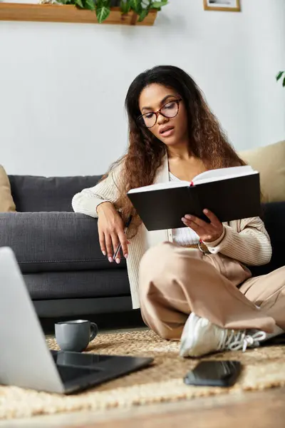 Uma mulher focada gosta de ler um livro enquanto se senta confortavelmente em sua convidativa sala de estar. — Fotografia de Stock