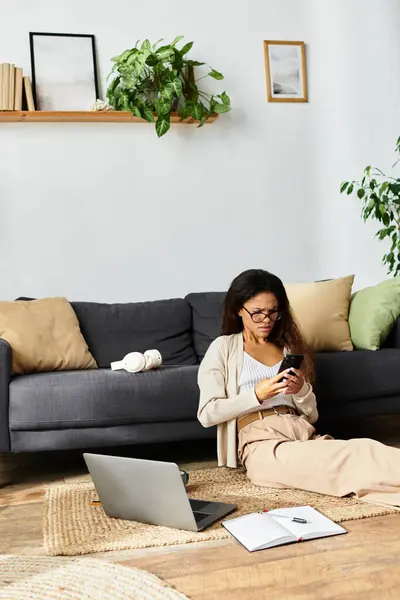 Dans un espace de vie confortable, une femme s'assoit sur le sol, utilisant intensément son smartphone. — Photo de stock