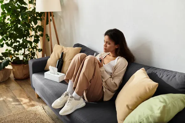 Die Frau genießt einen ruhigen Moment, sitzt gemütlich auf einem Sofa und nippt an ihrem Drink. — Stockfoto