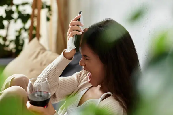 A cheerful woman holds a glass of red wine, laughing and relaxing in a cozy atmosphere. — Stock Photo