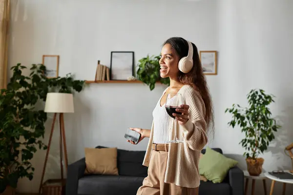 This happy woman relishes tunes, savoring wine in a stylish, inviting living space. — Stock Photo