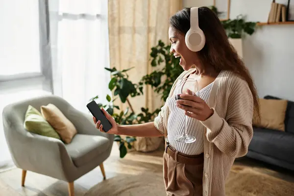 Una donna in un accogliente spazio di vita canta gioiosamente mentre tiene un drink e gode della musica. — Foto stock