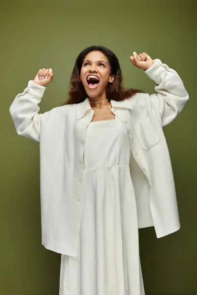 A cheerful woman expresses her excitement while dressed in a flowing white dress and light jacket — Stock Photo