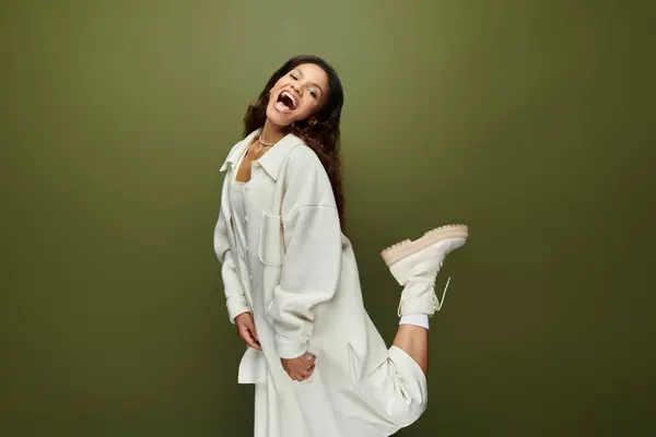 A carefree woman with a bright smile playfully poses, showcasing her stylish outfit and charm. — Stock Photo