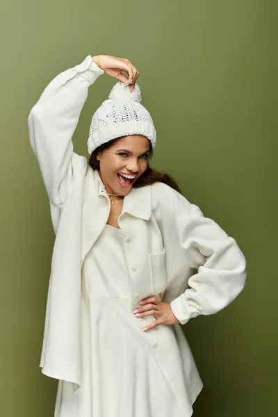 Uma mulher de roupa branca brinca com seu chapéu enquanto usa um sorriso brilhante. — Fotografia de Stock