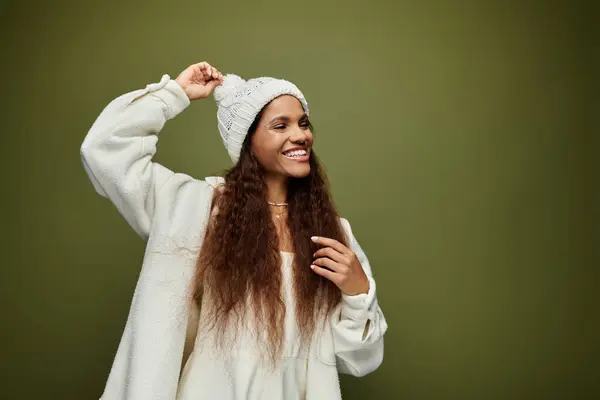 A cheerful woman with long hair enjoys a moment while wearing a warm beanie and sweater. — Stock Photo