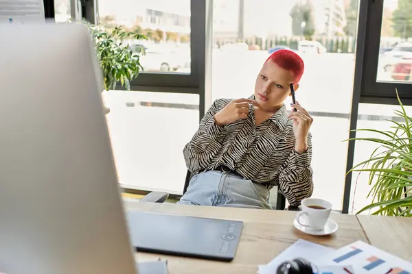 A bald woman with bold hair color ponders her next move in a bright workspace. — Stock Photo