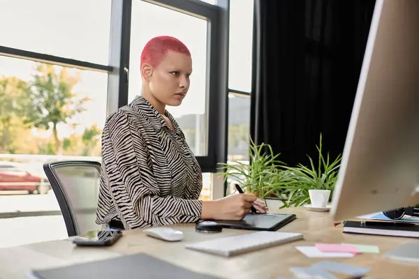Uma mulher careca elegante se envolve em tarefas criativas em sua mesa, cercada por vegetação e luz. — Fotografia de Stock