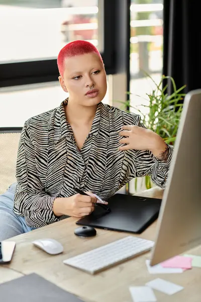 A bald woman with vibrant red hair engages in creative work at her stylish desk filled with plants. — Stock Photo