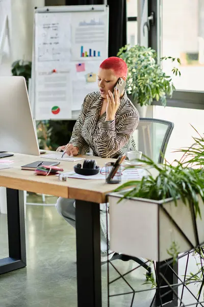 This creative professional communicates thoughtfully on the phone while working at her desk. — Stock Photo