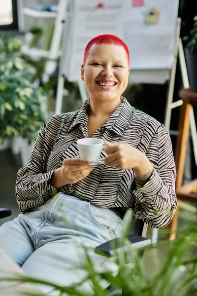 A joyful bald woman savors her coffee in a stylish and vibrant office environment. — Stock Photo
