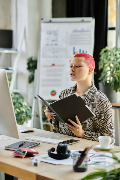 A bald woman with vibrant pink hair studies papers at her desk, surrounded by plants. — Stock Photo