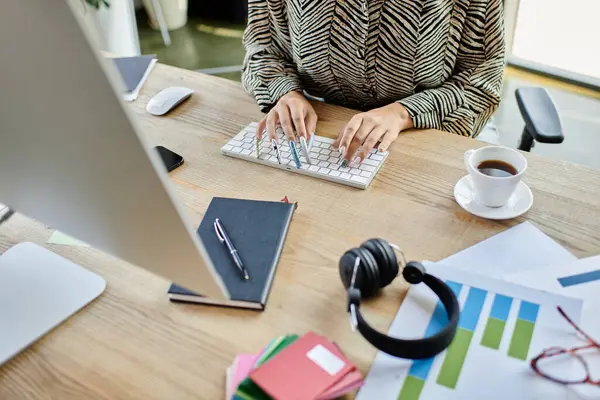 A bald woman types intently on a laptop amidst colorful stationery at her workspace. — Stock Photo