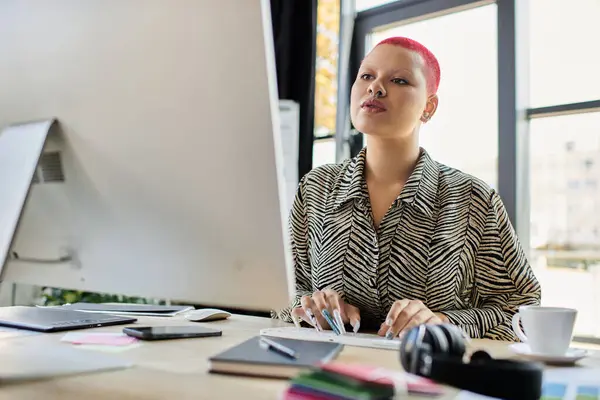 A confident woman with a shaved head is deeply engaged in her work at a stylish desk. — Stock Photo