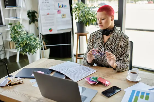 Uma mulher careca em uma roupa elegante se concentra na papelada, enquanto sentado em uma mesa adornada com plantas. — Fotografia de Stock