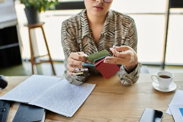 A fashionable bald woman analyzes vibrant accessories while enjoying a warm beverage. — Stock Photo