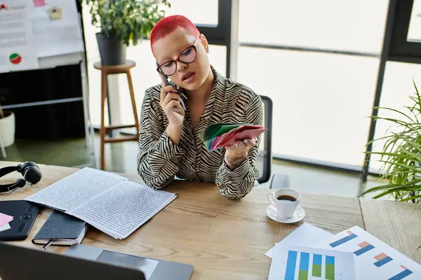 The bald woman in a stylish outfit speaks thoughtfully on the phone while analyzing colorful charts. — Stock Photo