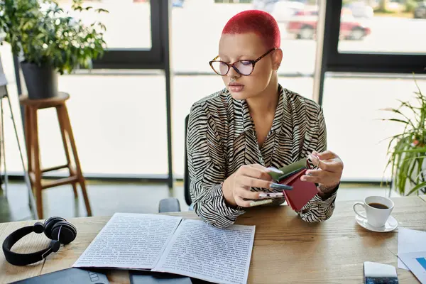 The focused woman reviews vibrant sketches while surrounded by a cozy workspace filled with plants. — Stock Photo