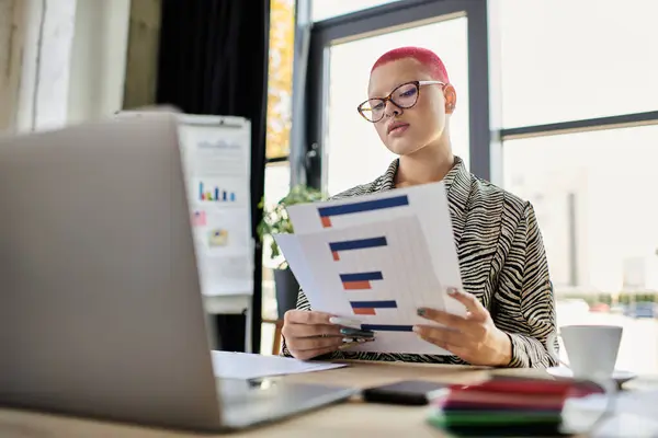 A confident bald woman reviews financial documents at a sleek desk in a vibrant office. — Stock Photo