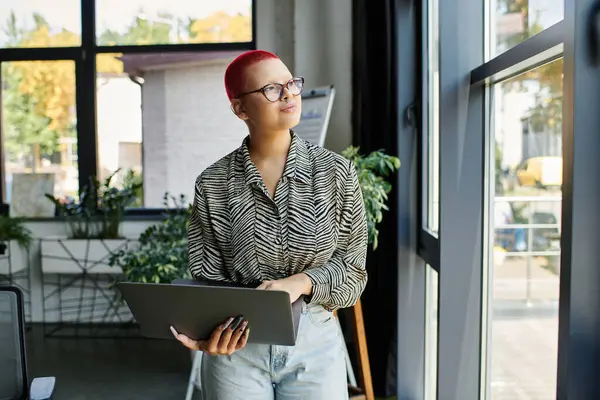 A bald woman with vibrant hair enjoys a moment of reflection while working in a stylish office. — Stock Photo