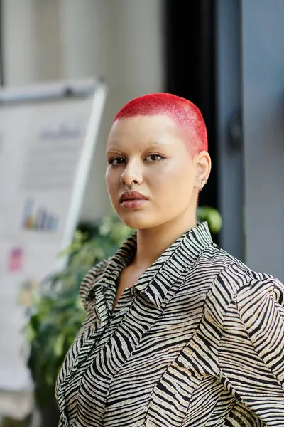 A confident person showcases vibrant red hair in a trendy outfit under soft lighting. — Stock Photo