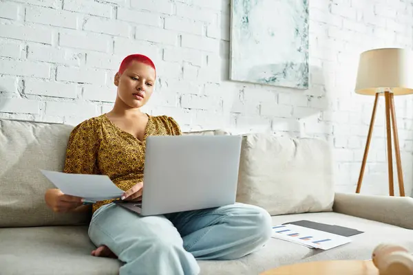 The bald woman engages with her laptop, surrounded by serene decor and natural light. — Stock Photo