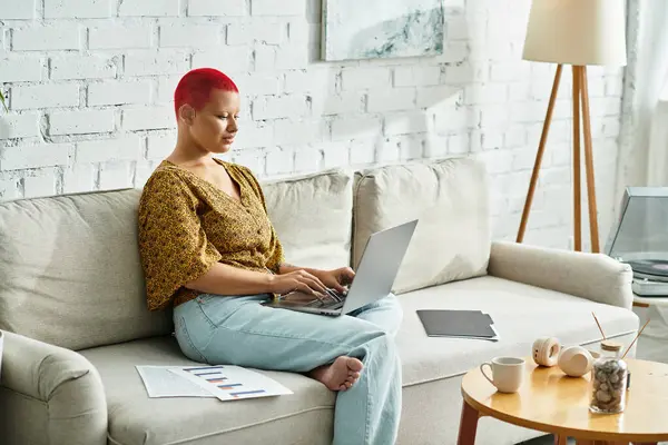 A bald woman works on her laptop in a stylish, bright, and cozy space. — Stock Photo