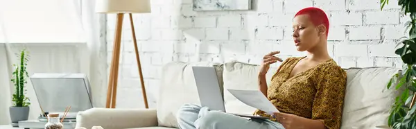 A bald woman with vibrant hair color enjoys a moment of creativity while relaxing indoors. — Stock Photo